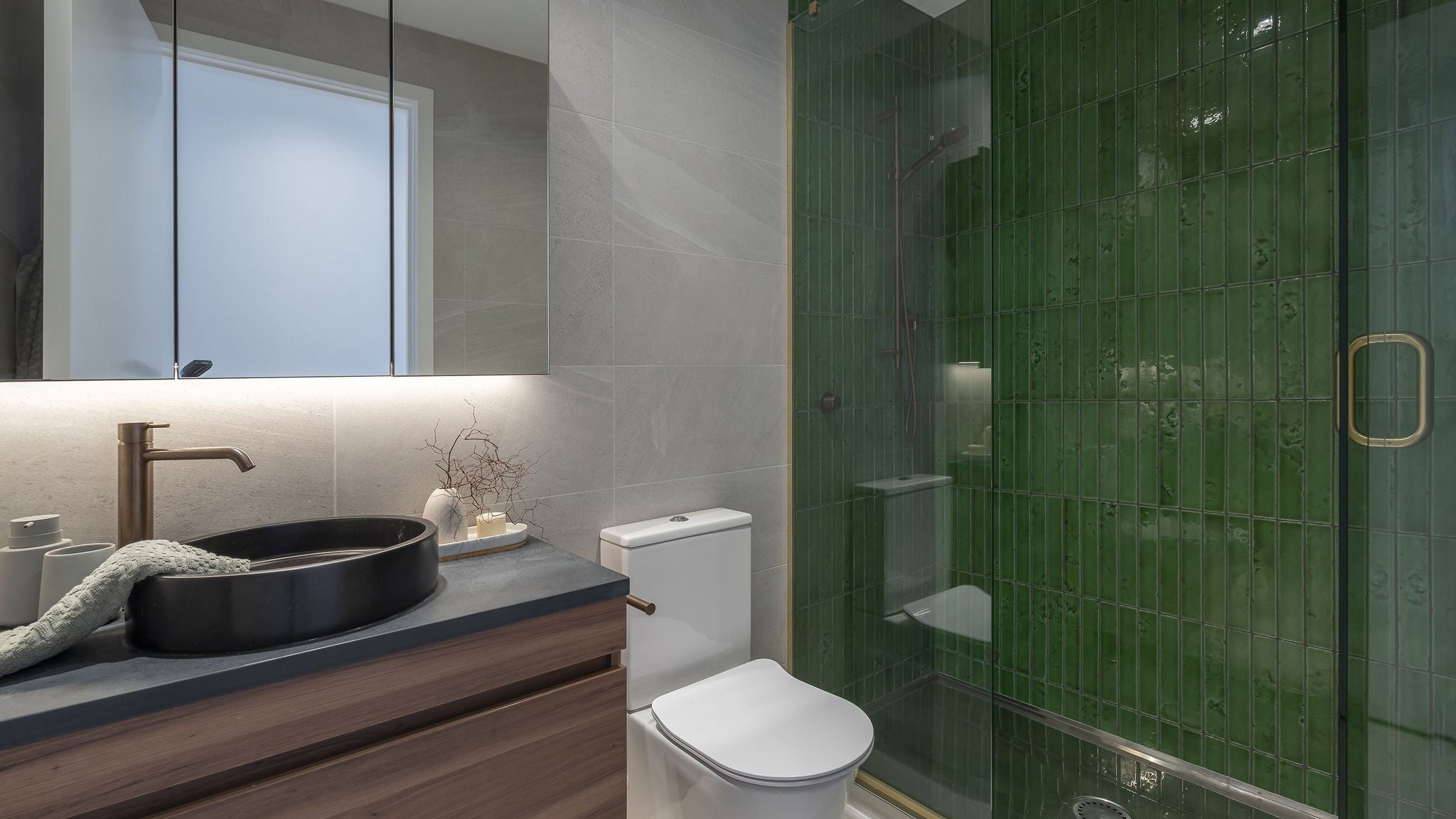 Bathroom with green tiles in the shower, modern layout for basin.