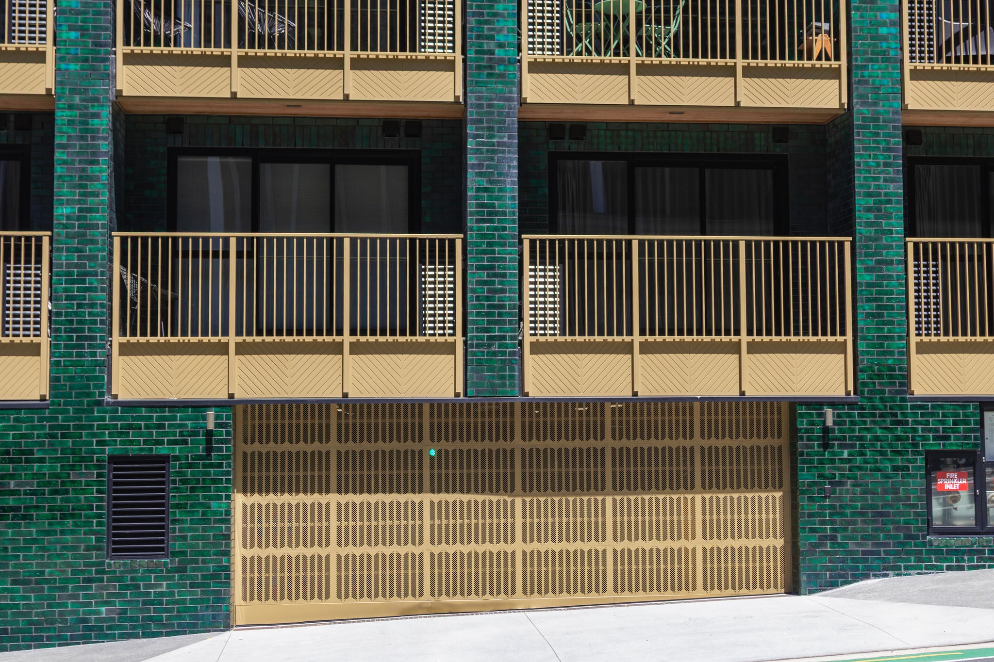 Cream coloured  carpark entrance way and matching balcony fencing above.