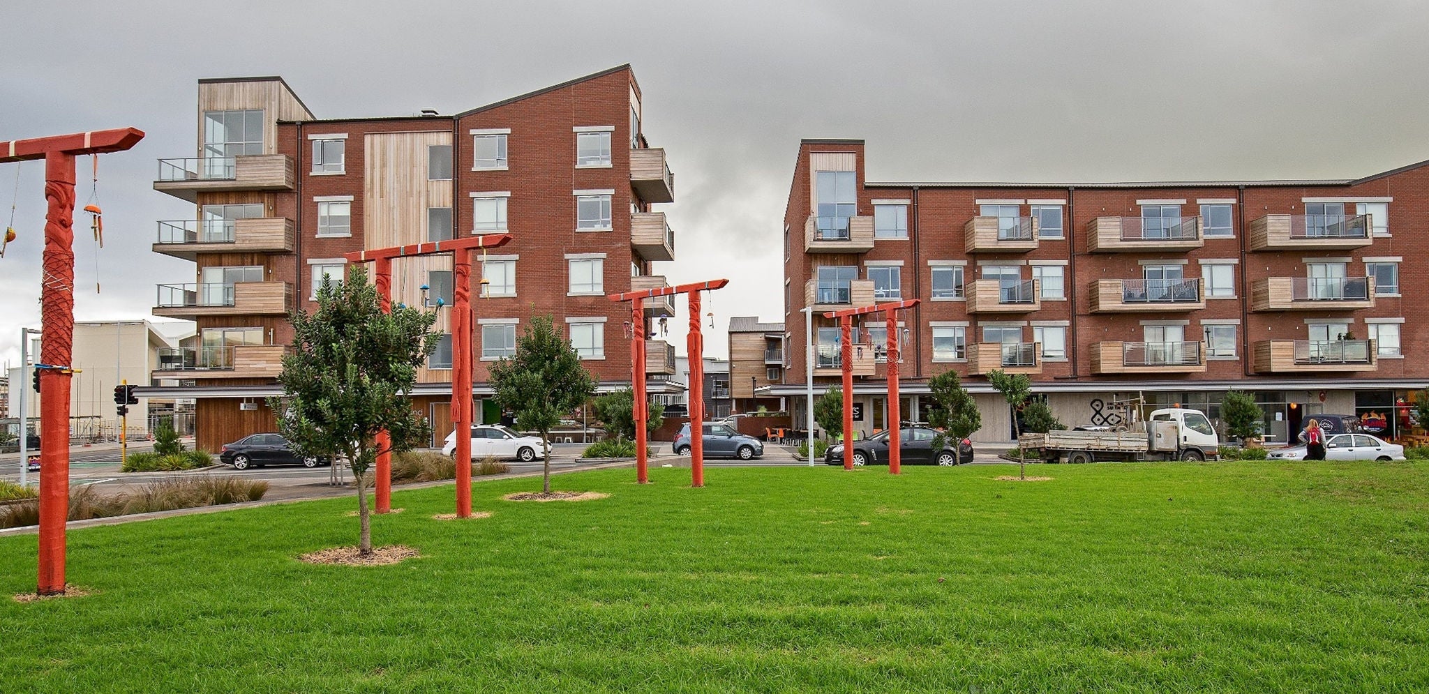 Neighbourhood and Subdivision image Two apartment blocks hem in park in the foreground. Their bottom storeys are dedicated retail space. In the park, there are red post and lintel-style public artworks.