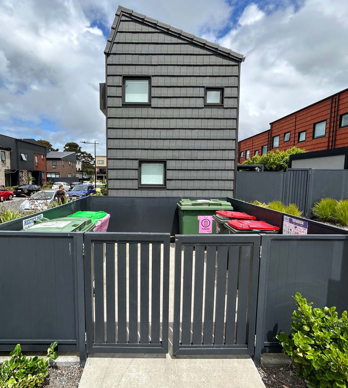 Looking at the end of the bloc with an enclosure with bins. 