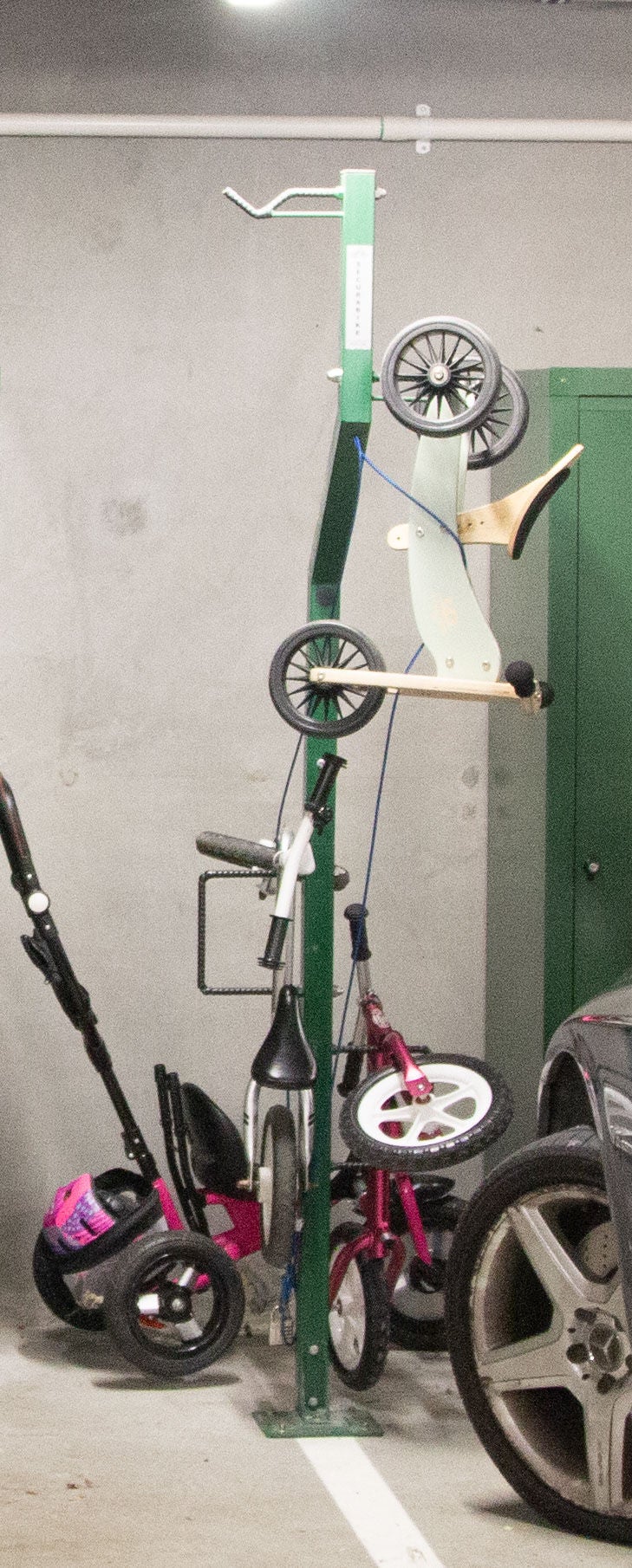 Kids bicycles hanging off a tall bike tree in the basement.