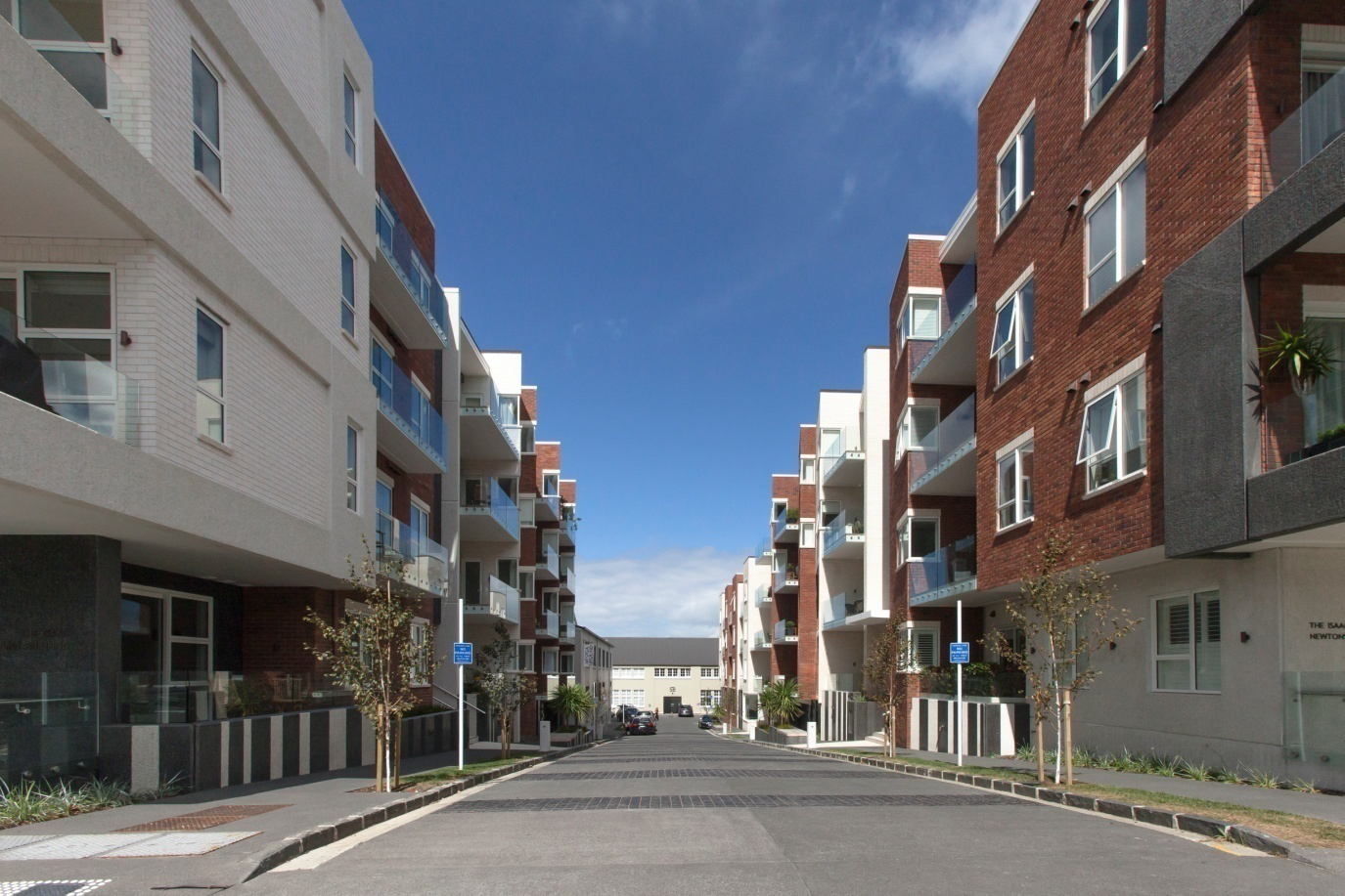 Looking down the joal lined with trees, with the buildings set back from the street.