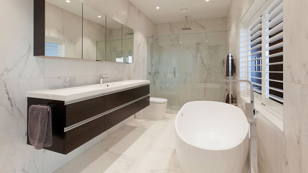 Luxuriously designed with marble, privacy slats, bath and large vanity, this bathroom also includes a shower and toilet.