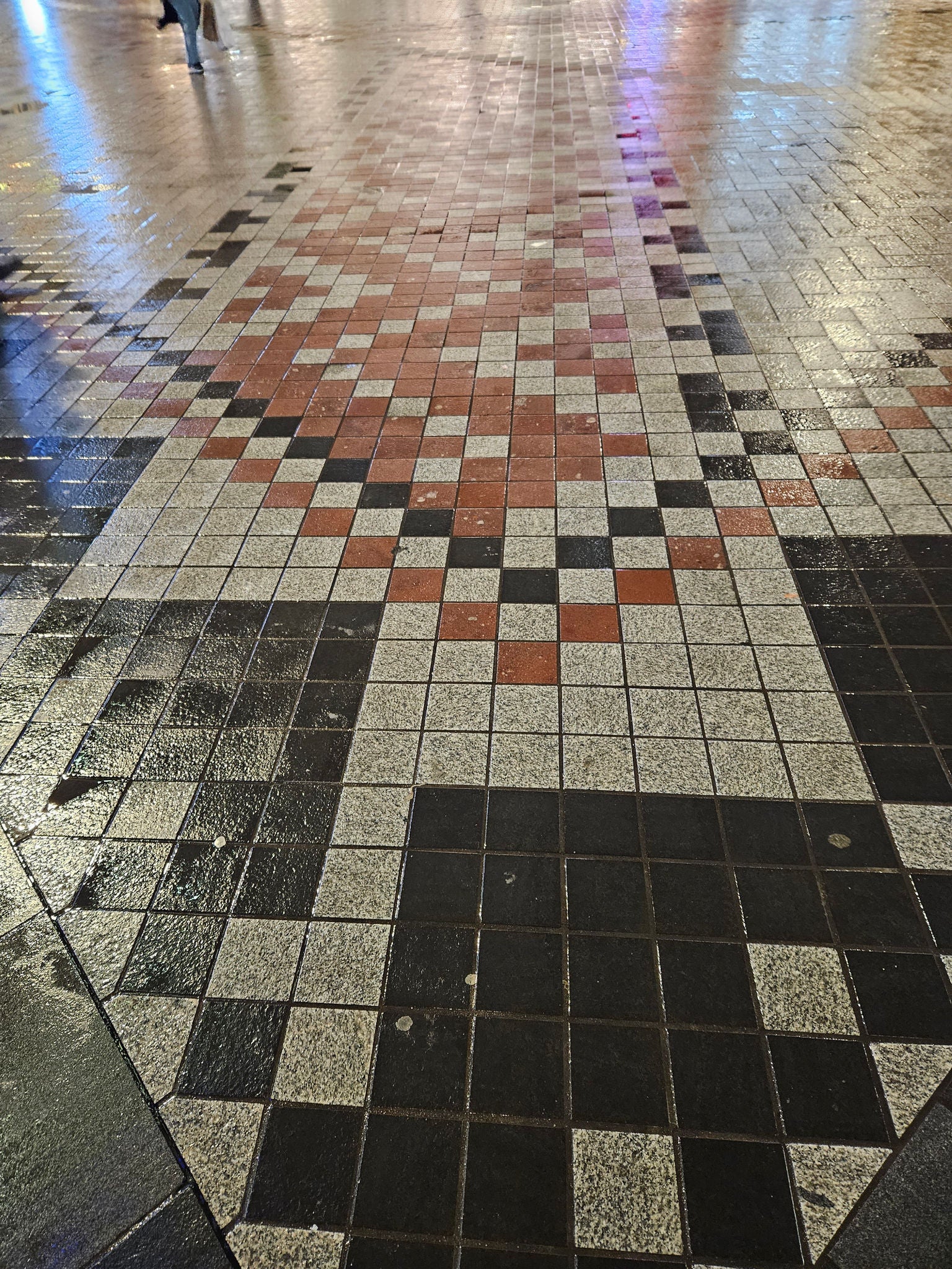 A photo of the paving whāriki at night time. The pavers are a mix of white, red and black pavers.