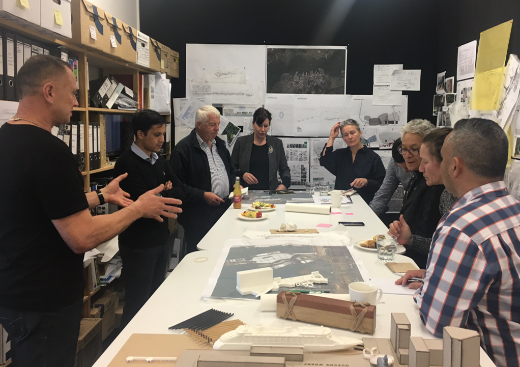 Mana Whenua kaitiaki (guardians) and designers are grouped around a table with plans and models engaged in the co-design process at Isthmus’ studio.  