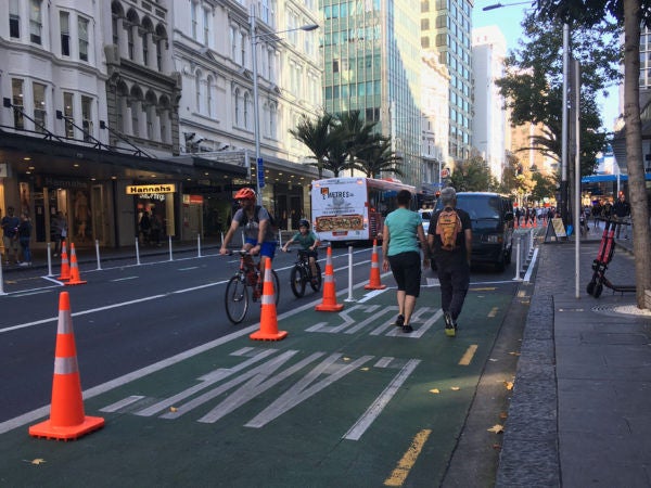 People walking on Queen Street with traffic cones marking the edge of the extended footpath.