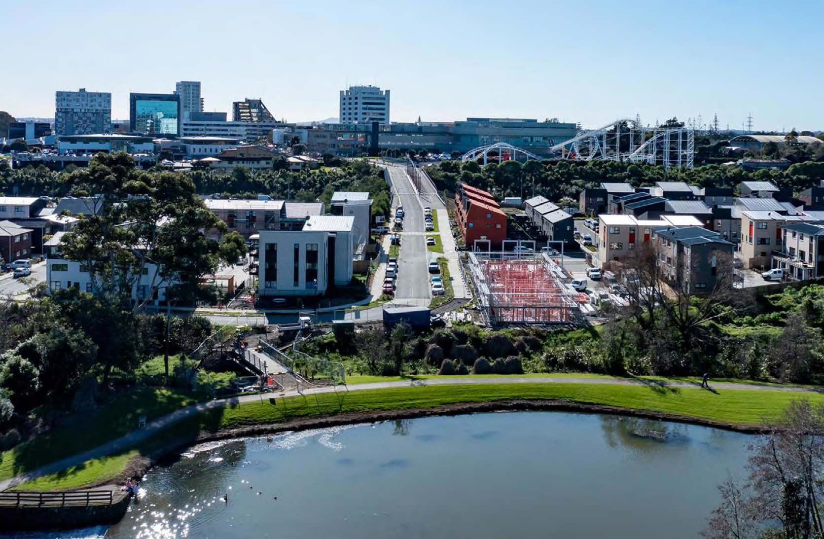 Looking over the development with the paond and reserve in the foreground and the town centre and Rainbow's End ride in the background.
