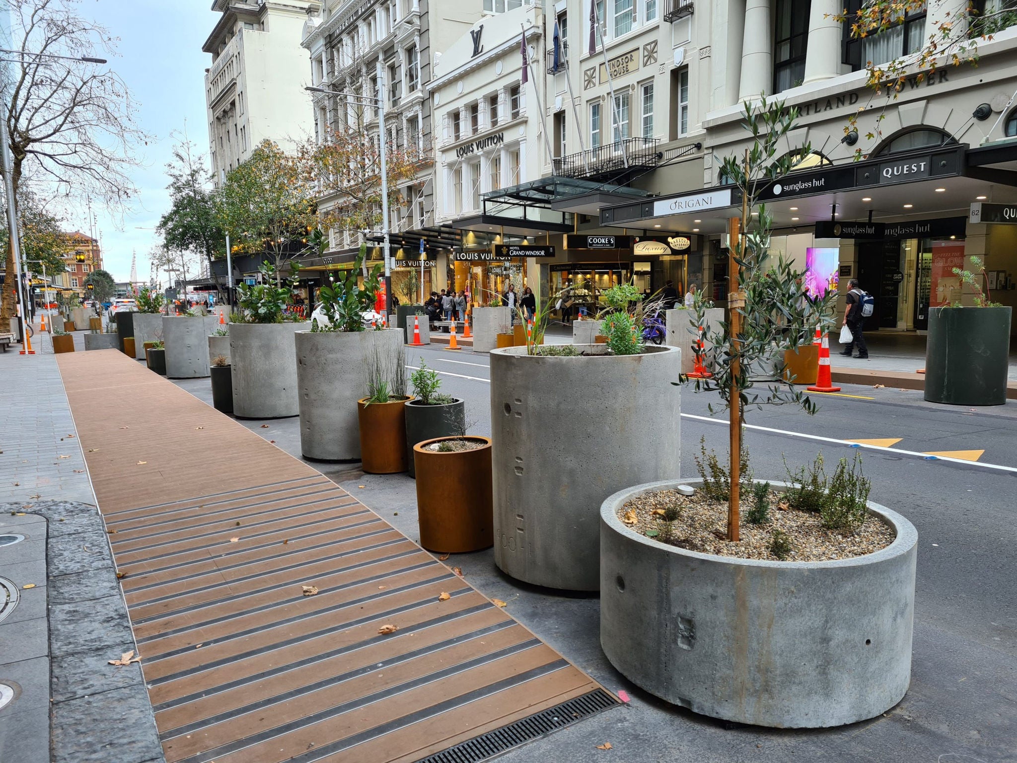 A timber boardwalk and concrete planters along Queen Street. 
