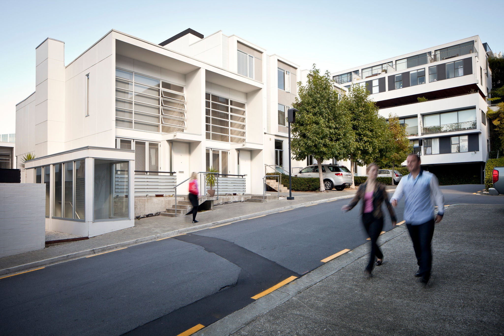 The terrace facade is bright in the sunny afternoon light, with bold modern lines offset by leady trees.