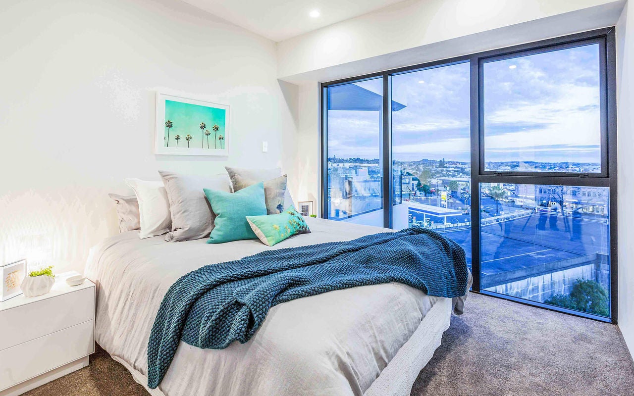 Plush feel of carpet with a queen sized bed and side table, views to the Waitakeres.