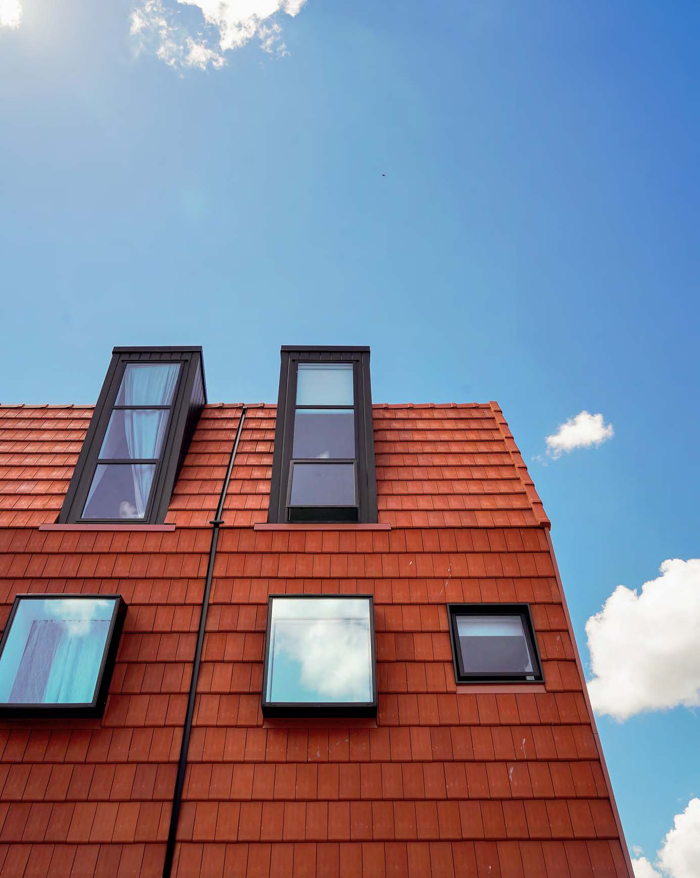 Looking up at the facade of the building and the clay tiles and windows. 