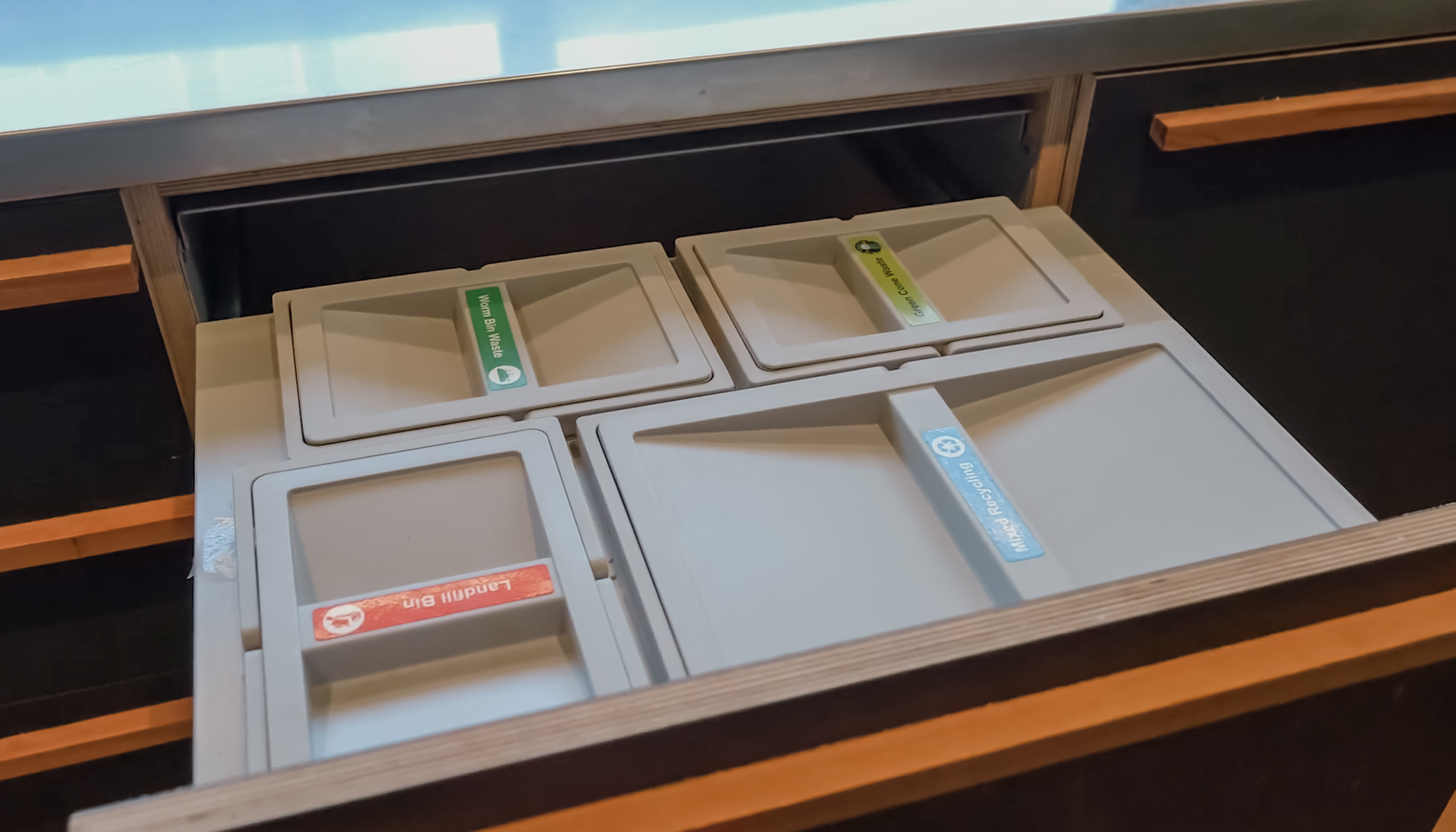 A kitchen drawer with four different waste bins. 