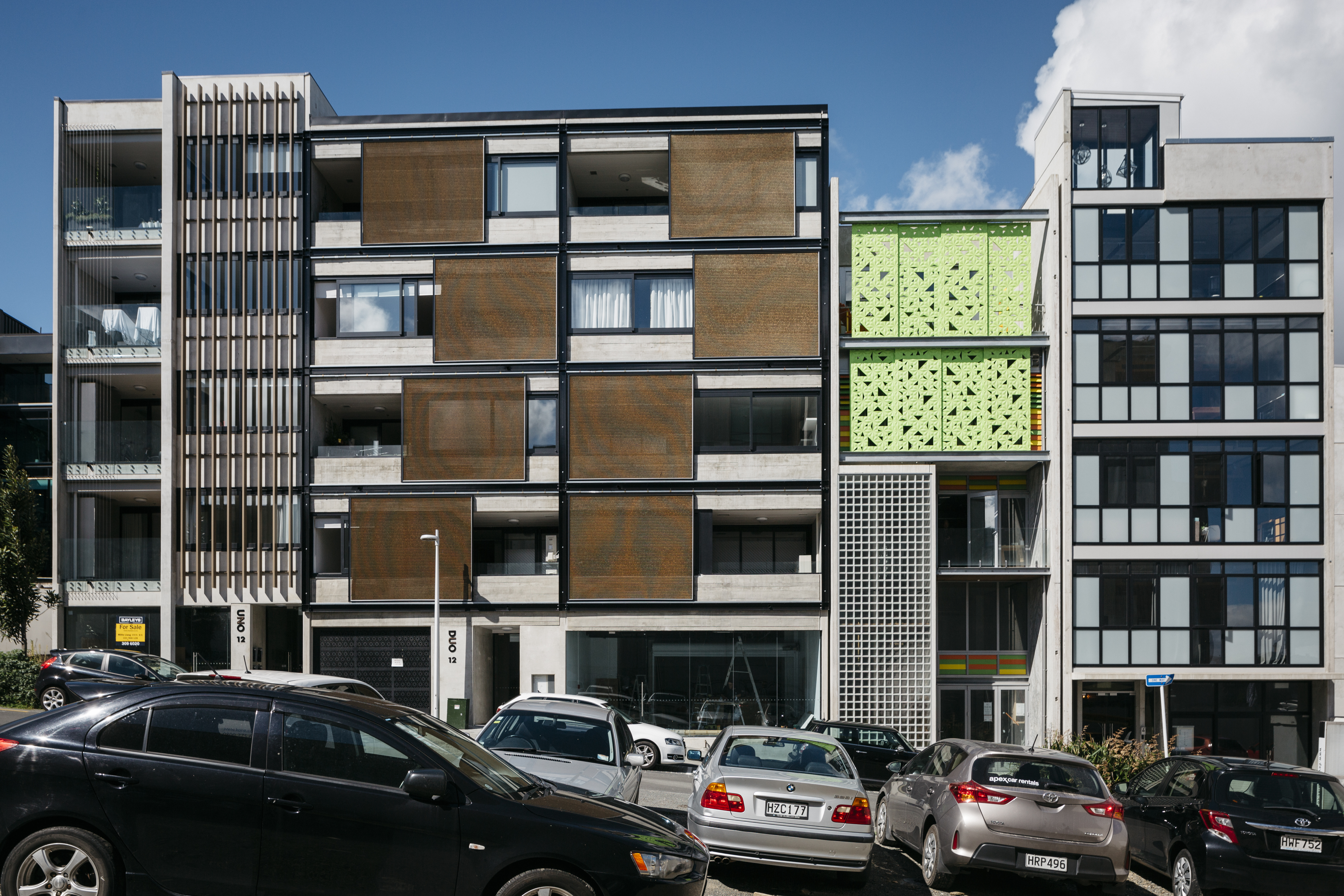 Front on view across the street, looking at 3 different 5-6 storey apartments on Vinegar Lane, with cars parked out front.