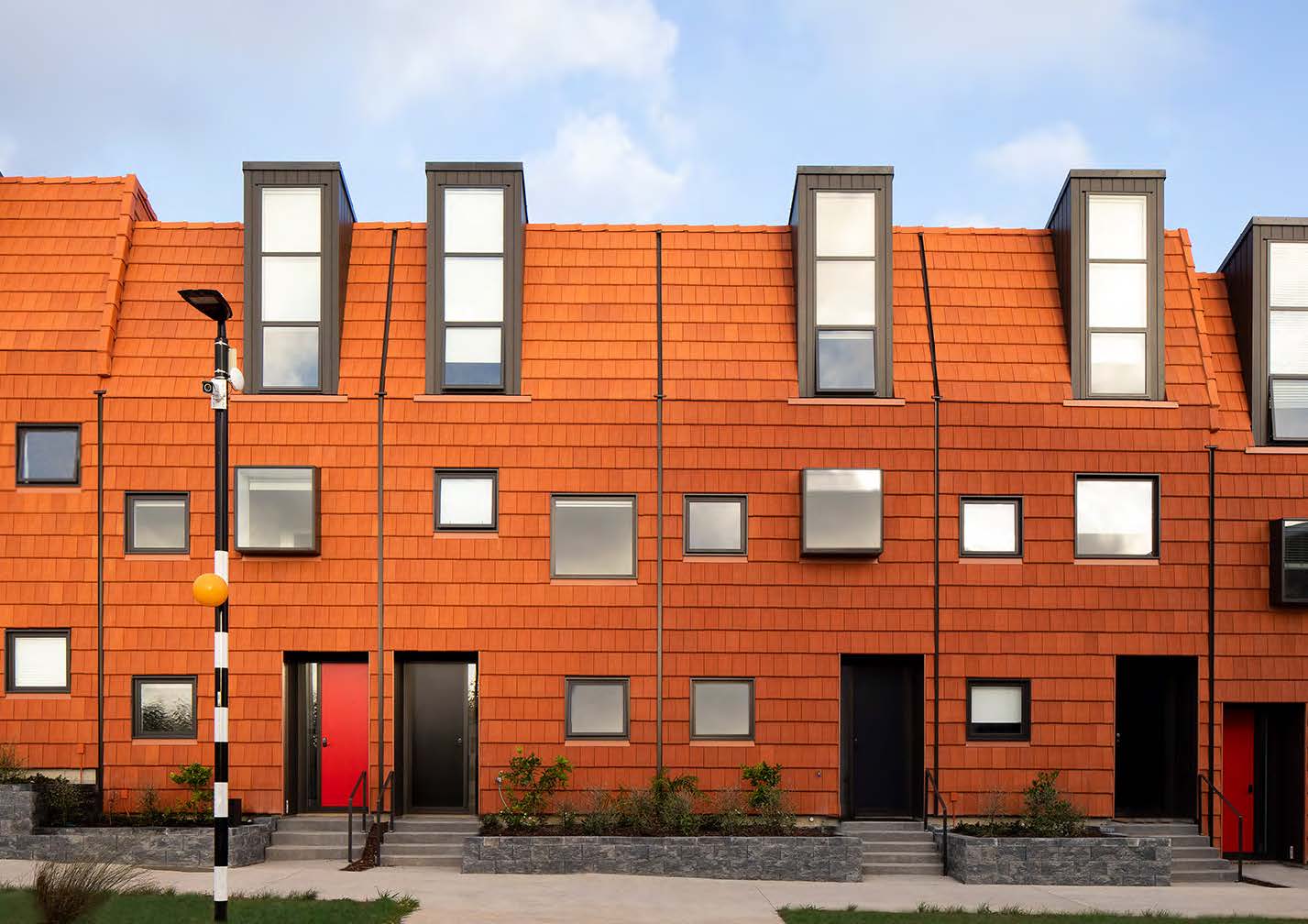 Looking across the street at the orange tiled facade of the townhouses. 