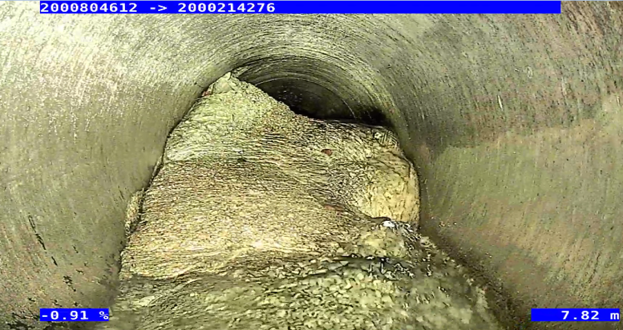 Looking at the concrete blockage inside the pipe through a scope.
