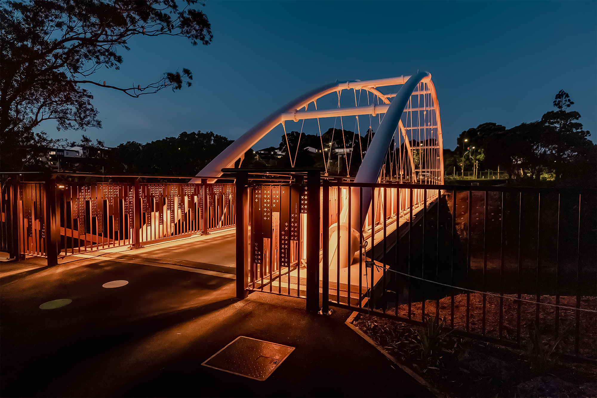 A walking and cycling bridge that connects the two sides of the Panmure Lagoon, displaying the Māori and Croatian patterns in the metal railing detail, as well as the nighttime lighting design. 