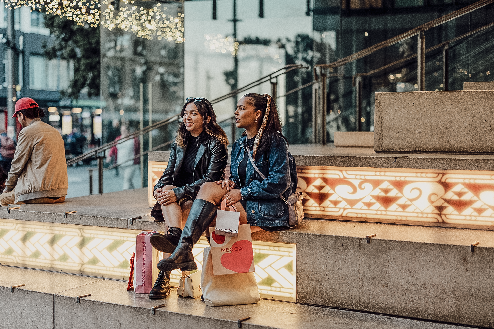 People sitting on the civic steps at the entrance to Commercial Bay. The steps include an immersive light feature on the risers with two Māori designs, one reflecting the whariki (woven welcome mat), and the other reflecting the volcanic activity of the Tāmaki Isthmus and arrival of outsiders to New Zealand.