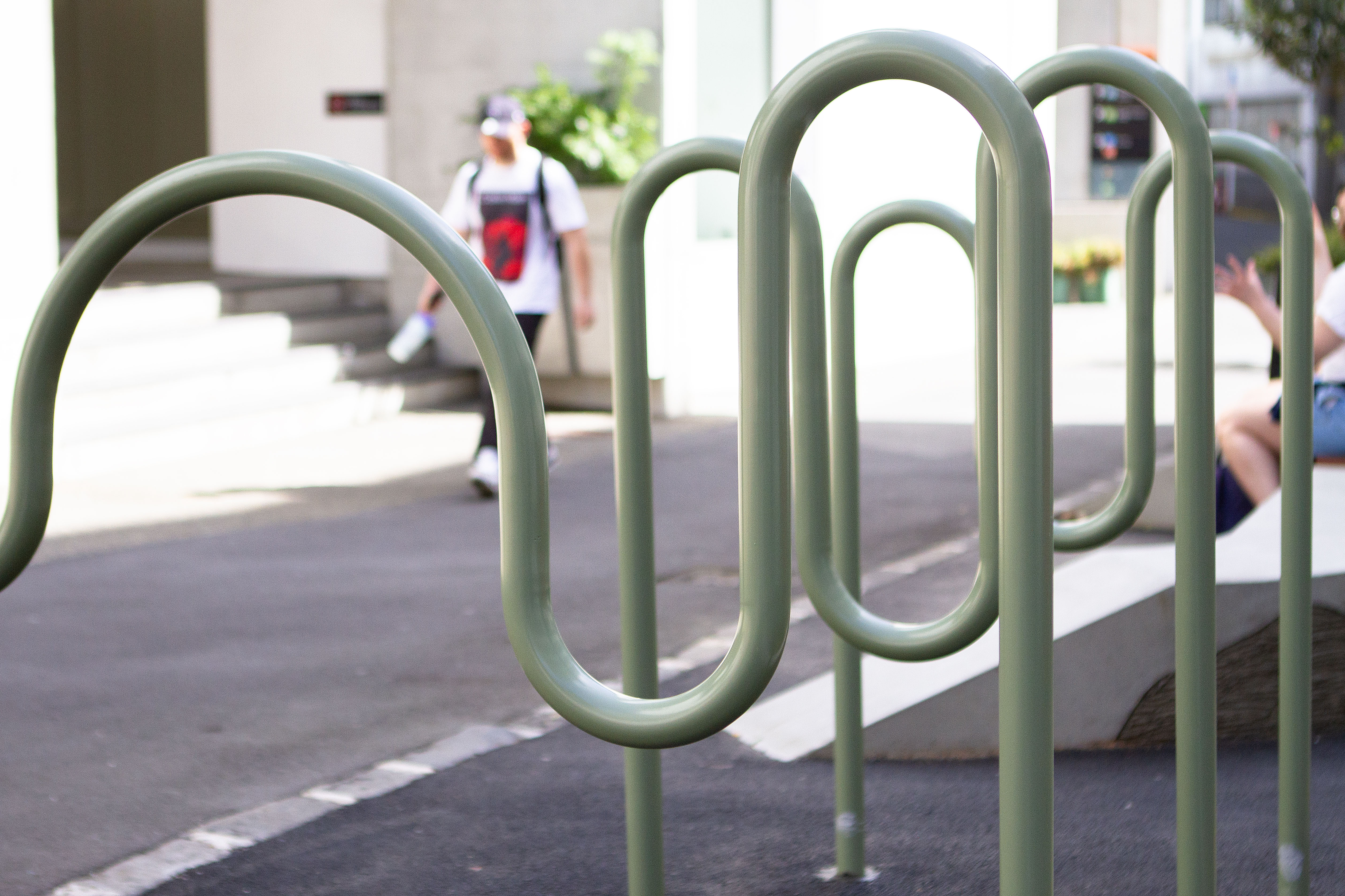 Green metal bike racks on St Paul street in downtown Auckland. The metal is bent into curves reminiscent of a winding stream. This is so reference the Waihorotiu Stream running under Queen Street.